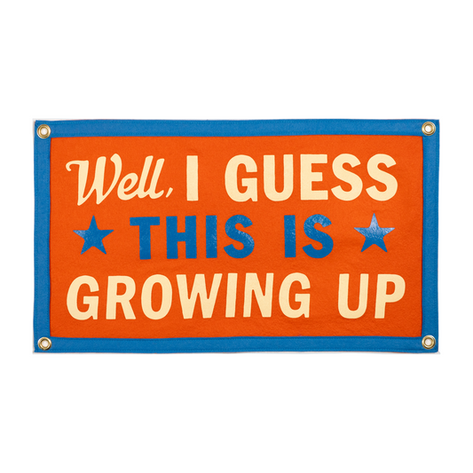 Orange felt banner with cream text 'Well, I guess this is growing up' and a blue border